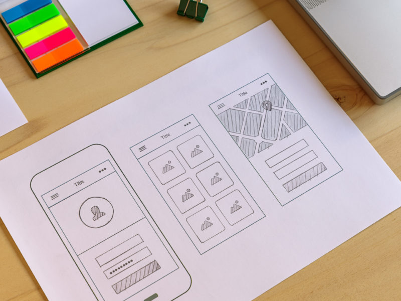 Mobile app prototype on designer wooden desk.